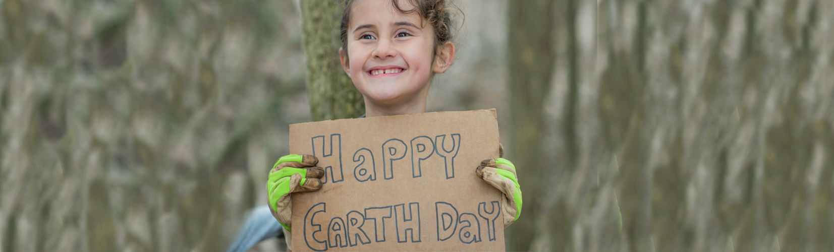 Young girl holding cardboard with Happy Earth Day text
