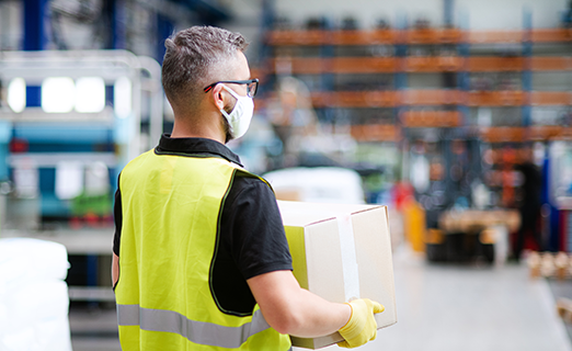 Person trägt Kartonpaket in Lagerhaus