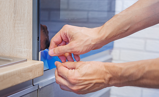 person removing surface protection film on oven