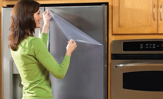 person removing surface protection on refrigerator